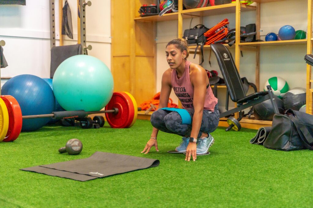 Fit woman in activewear crouching during workout in an Orlando gym.