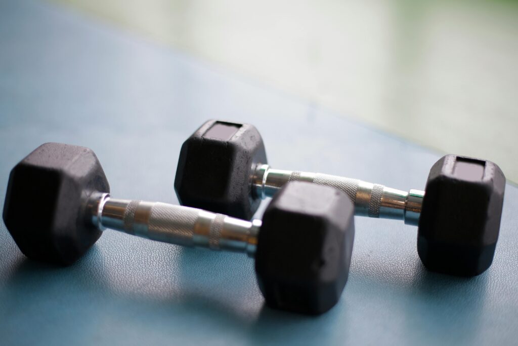 Close-up view of two black hex dumbbells on a gym floor, perfect for fitness content.